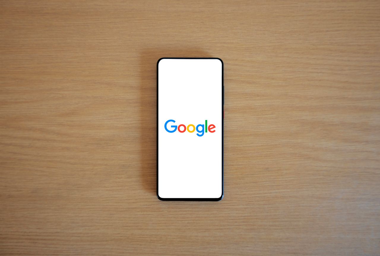 Un smartphone affichant la page d’accueil de Google sur une surface en bois, vu de dessus.